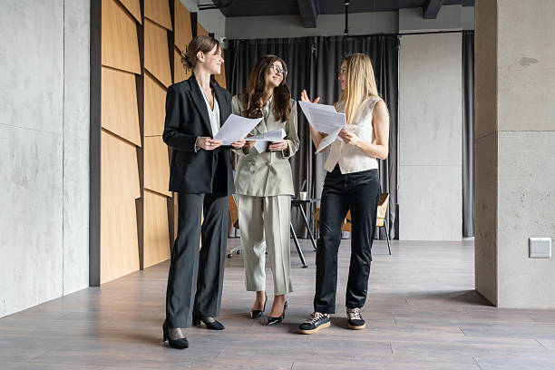 Colleagues having a brief standing discussion near a bright office window during a movement break